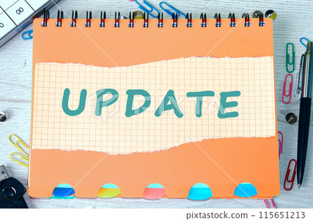 Business concept. UPDATE text on a piece of torn-off sheet of a checkered notebook lying on a notebook 115651213