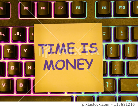 Business concept. Copy space. The words TIME IS MONEY on a yellow sticker lying on the keyboard with a colored backlight Business concept. Copy space. The words TIME IS MONEY on a yellow sticker lying on the keyboard with a colored backlight 115651216