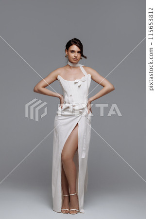 Woman in a white wedding dress on a gray background. 115653812