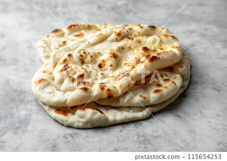 Stack of fresh naan breads on a grey surface, perfect for any meal 115654253