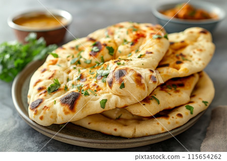 Hand scooping creamy curry with naan bread, highlighting traditional Indian flavors 115654262