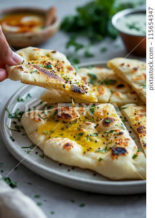 Naan bread dipped in a creamy curry sauce, a traditional Indian meal setup 115654347
