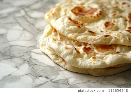 Soft, fluffy naan breads stacked on a marble background, ready to enjoy 115654348
