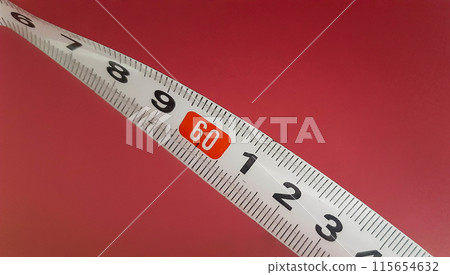 Measuring tape on a pink background. Construction tape measure a mark - 60 cm. Measuring tape on a pink background. Construction tape measure a mark - 60 cm. 115654632