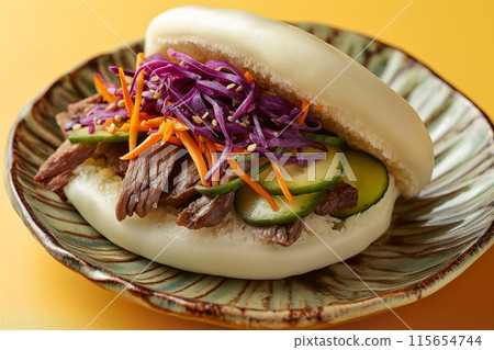 Beef bao on a ceramic plate with cucumber and purple cabbage on yellow 115654744