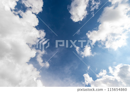 Gazing at a blue sky with fluffy white cumulus clouds. 115654860