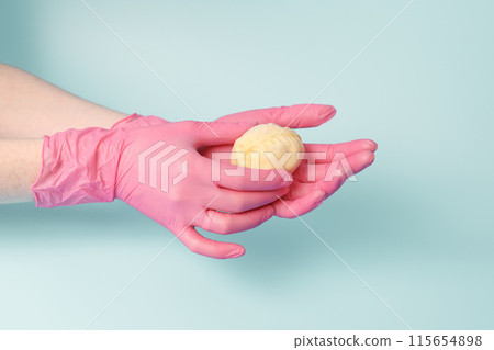 Close-up on female hands of a cook in rubber gloves holding raw mantu from dough with meat, concept of neat production of semi-finished food. 115654898