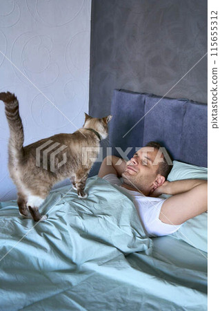 a young man sleeping with a cat on his chest, morning routine a young man sleeping with a cat on his chest, morning routine 115655312