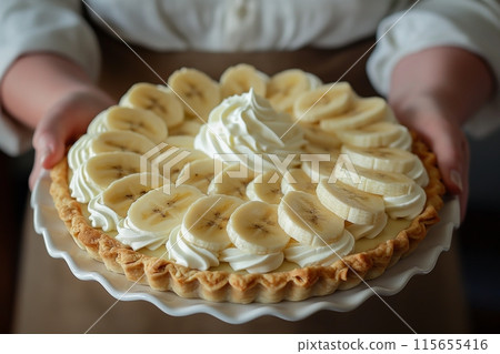 Banana cream pie in hands, featuring perfect slices and a creamy whipped center 115655416