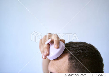 a man massages his head with an massager for hair growth a man massages his head with an massager for hair growth 115655632