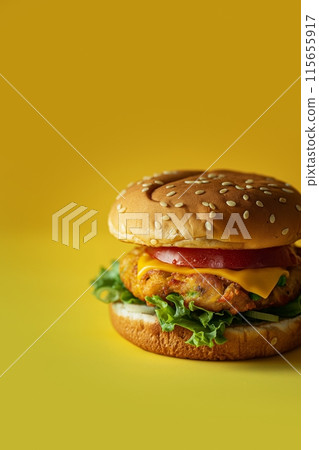 Vibrant McAloo Tikki burger with lettuce and cheese on a sesame seed bun against a yellow backdrop 115655917