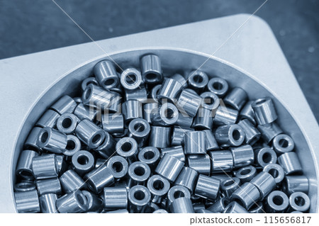 The pile of machined metal cylinder shape parts in the light blue scene. 115656817