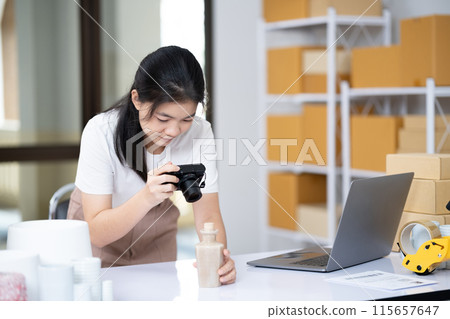 Young Asian business entrepreneur using a compact digital camera take a photo of product for upload to website online shop. 115657647