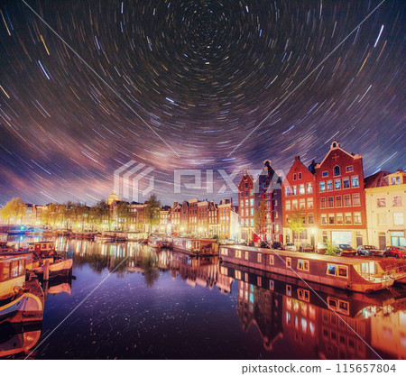 Beautiful night in Amsterdam. Night illumination of buildings and boats near the water in the canal. Beautiful night in Amsterdam. Night illumination of buildings and boats near the water in the canal. 115657804