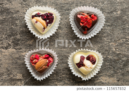 chocolate sweets in the form of a heart with fruits and nuts on a colored background. top view with space for text, holiday concept 115657832