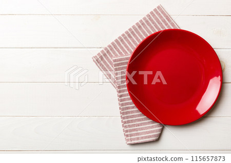Top view on colored background empty round red plate on tablecloth for food. Empty dish on napkin with space for your design Top view on colored background empty round red plate on tablecloth for food. Empty dish on napkin with space for your design 115657873