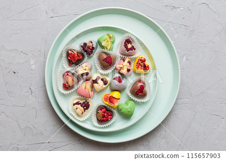Plate with different chocolate on colored background. Assortment of fine chocolates top view vith copy space Health and obesity concept Plate with different chocolate on colored background. Assortment of fine chocolates top view vith copy space Health and obesity concept 115657903