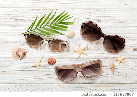 sunglasses with seashell lying on table background. Sunglasses on summer background. Top view flat lay with copy space for text 115657907