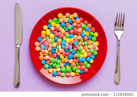 cutlery on table and sweet plate of candy. Health and obesity concept, top view on colored background 115658085