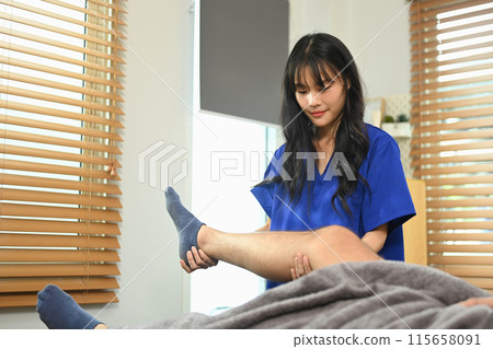 Physiotherapist doing manual therapy, treating injured knee of male athlete patient in clinic 115658091