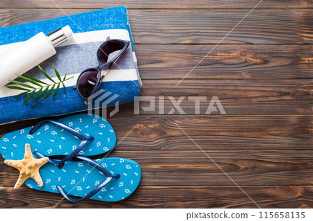 Summer holiday concept. Top view of beach towel, flip flop and sunscreen cream on table Top view with copy space for text 115658135