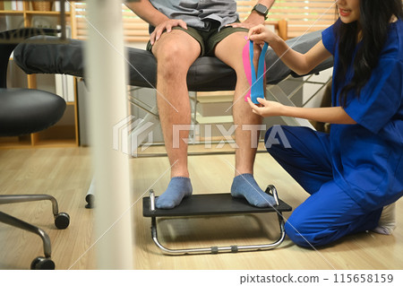 Physiotherapist applying elastic kinesiology tape on patient knee. Sport physical therapy concept 115658159