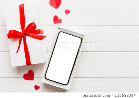 Opened gift box with ribbon and phone on color background, top view. Blank open box packaging mockup , Template for your design - branding mockup Opened gift box with ribbon and phone on color background, top view. Blank open box packaging mockup , Template for your design - branding mockup 115658384