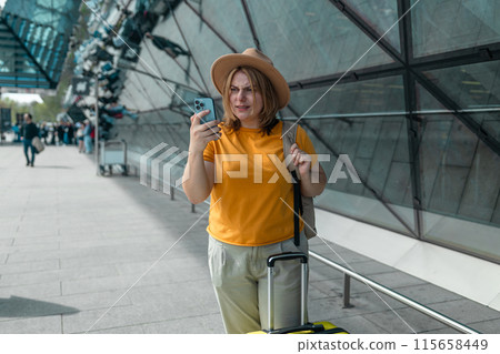 Happy traveling Caucasian woman in stylish casual clothes and hat uses mobile smartphone, checking trip destination on Internet. Female waiting at flight gates for plane boarding, smiling have a Happy traveling Caucasian woman in stylish casual clothes and hat uses mobile smartphone, checking trip destination on Internet. Female waiting at flight gates for plane boarding, smiling have a 115658449