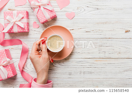 Flat lay of heart shaped cup of black coffee in the hands of women on colored background with copy space top view. Valentine day and holiday concept 115658540