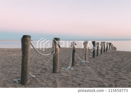 A row of wooden posts with rope tied to them on a beach A row of wooden posts with rope tied to them on a beach 115658773