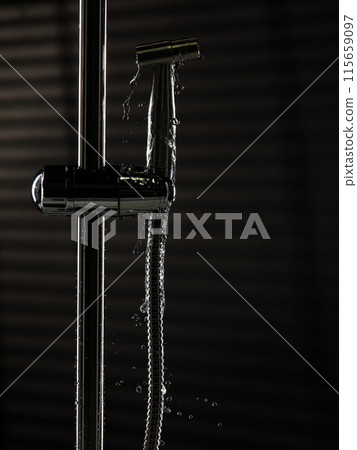 Bidet shower head leak water from hoses plumbing in bathroom as water clogged drop. Black background isolated. Leaking water from chromium stainless steel bidet shower head 115659097