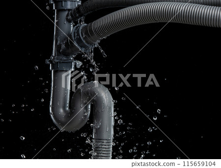 Leaking water from gray plastic pipe under sink. Drain leak water from pipe plumbing in bathroom as water clogged drop. Black background isolated 115659104