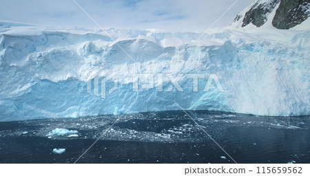 Massive glacier iceberg towering cold polar ocean in Antarctica. Global warming, ecology and climate change concept. Blue ice wall melting under sun. Arctic winter nature landscape aerial drone view. Massive glacier iceberg towering cold polar ocean in Antarctica. Global warming, ecology and climate change concept. Blue ice wall melting under sun. Arctic winter nature landscape aerial drone view. 115659562