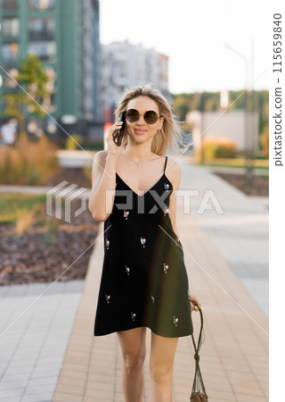 Young woman walking on city streets with while talking on her phone 115659840