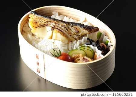 A bento box of grilled cod in saikyo-yaki style served in a bento box photographed against a black background 115660221
