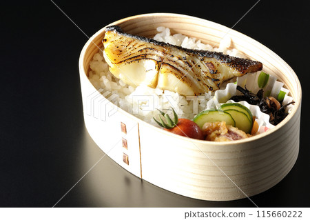 A bento box of grilled cod in saikyo-yaki style served in a bento box photographed against a black background 115660222