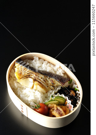 A bento box of grilled cod in saikyo-yaki style served in a bento box photographed against a black background 115660247