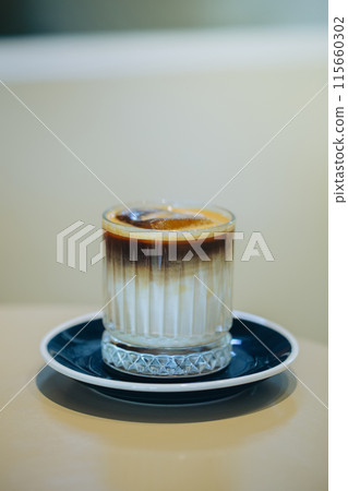 Elegant layered coffee in a clear glass, highlighting rich textures. Elegant layered coffee in a clear glass, highlighting rich textures. 115660302