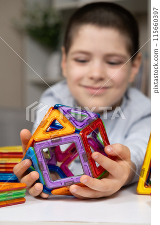 A child plays with a magnetic construction set. Interesting educational toys. A child plays with a magnetic construction set. Interesting educational toys. 115660397