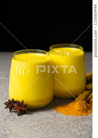 Golden milk, a traditional Ayurvedic drink with turmeric in two glasses on a black gray background Golden milk, a traditional Ayurvedic drink with turmeric in two glasses on a black gray background 115660444
