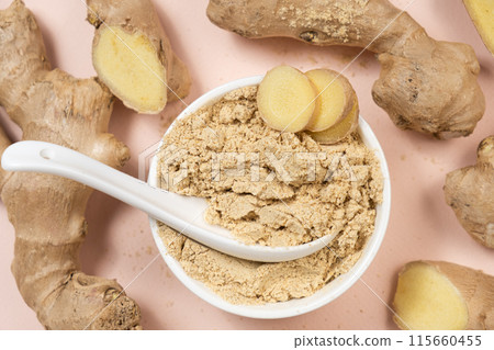 Ground ginger root powder natural spice seasoning on pink background 115660455