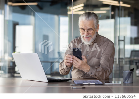 Senior businessman sitting at office desk using smartphone and laptop, working and communicating. Senior businessman sitting at office desk using smartphone and laptop, working and communicating. 115660554