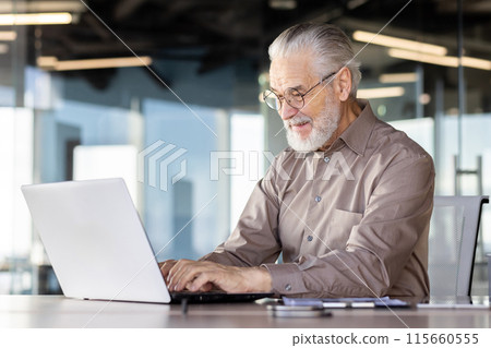 Senior businessman working on laptop at modern office desk. 115660555