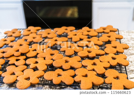Freshly baked gingerbread cookies find their place on a cooling wire rack in a modern white kitchen, filling the air with festive aromas. Freshly baked gingerbread cookies find their place on a cooling wire rack in a modern white kitchen, filling the air with festive aromas. 115660623