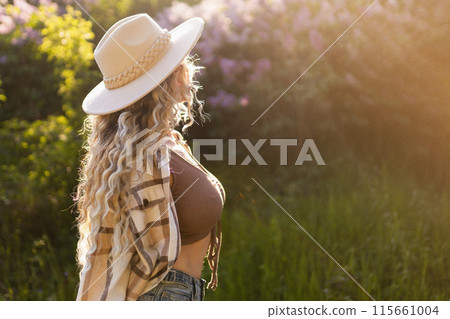 Girl with curly hair at sunset near flower trees Girl with curly hair at sunset near flower trees 115661004