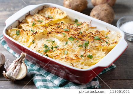 Potato gratin baked with cream and cheese on wooden table. Close up Potato gratin baked with cream and cheese on wooden table. Close up 115661061