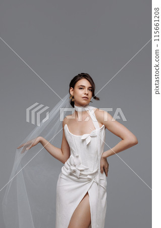 Woman in a white wedding dress on a gray background. 115661208