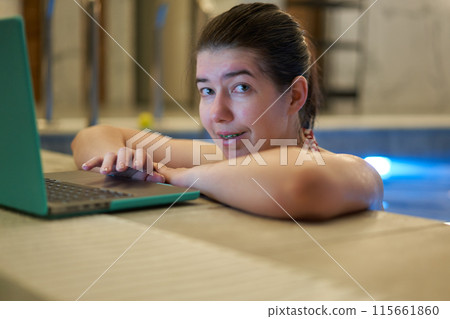Woman Smiling While Using Laptop in Swimming Pool 115661860