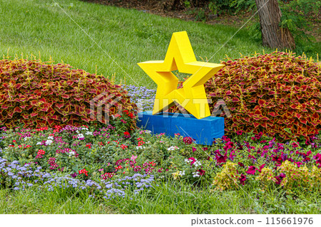 yellow star next to a flowerbed of flowers on green grass 115661976