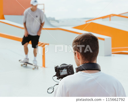 Videographer filming skateboarding in skatepark 115662792